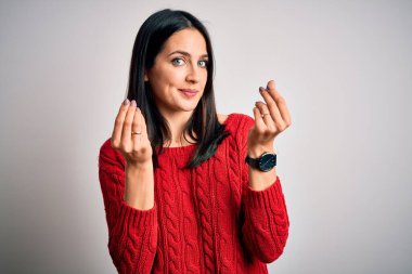 Young brunette woman with blue eyes wearing casual sweater over isolated white background doing money gesture with hands, asking for salary payment, millionaire business
