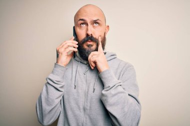 Sakallı yakışıklı kel bir adam akıllı telefonda konuşuyor ciddi bir yüz ifadesi var soru soruyor, çok karışık bir fikir.