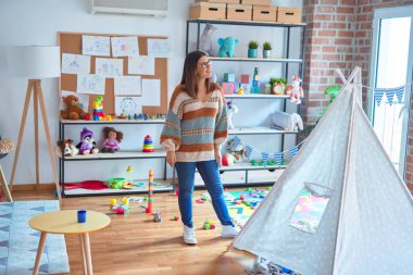 Genç, güzel öğretmen kadın mutlu ve kendinden emin gülümsüyor. Anaokulunda yüzünde gülümsemeyle dikiliyorsun.