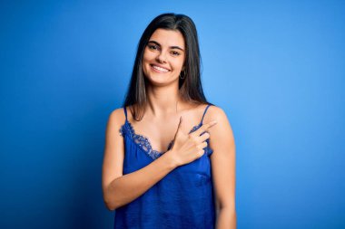 Zarif ve rahat mavi iç çamaşırı giyen genç ve güzel esmer kadın. Neşeli bir iç çamaşırı. Yüzünde mutlu ve doğal bir ifadeyle, elleri ve parmaklarıyla yüzünü gösteren bir gülümseme.