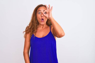 Orta yaşlı olgun bir kadın beyaz soyutlanmış arka planda duruyor. Şaşırmış bir yüz ve parmaklarından bakan bir gözle iyi bir hareket yapıyor. İnançsız ifade.
