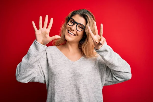 Jovem Mulher Loira Bonita Vestindo Suéter Óculos Sobre Fundo Vermelho — Fotografia de Stock