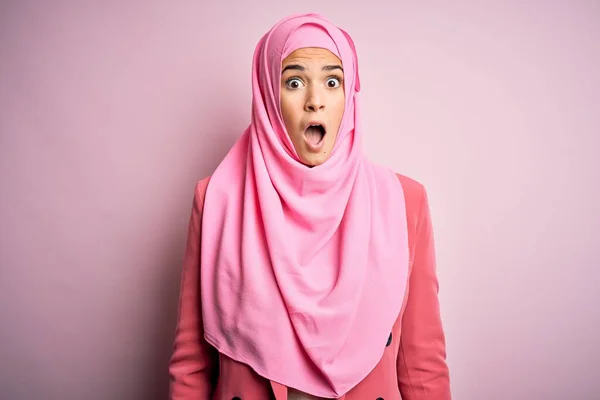 若いです美しいです女の子身に着けていますムスリムヒジャーブ立って上の隔離されたピンクの背景恐怖と衝撃で驚きと驚きの表情 恐怖と興奮した顔 — ストック写真