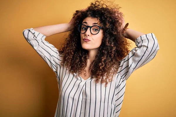 Young beautiful woman with curly hair and piercing wearing striped shirt and glasses Doing bunny ears gesture with hands palms looking cynical and skeptical. Easter rabbit concept.