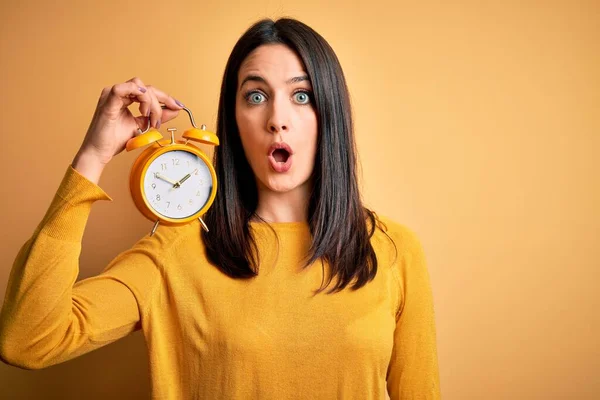 Jovem Mulher Com Olhos Azuis Segurando Despertador Sobre Fundo Amarelo — Fotografia de Stock