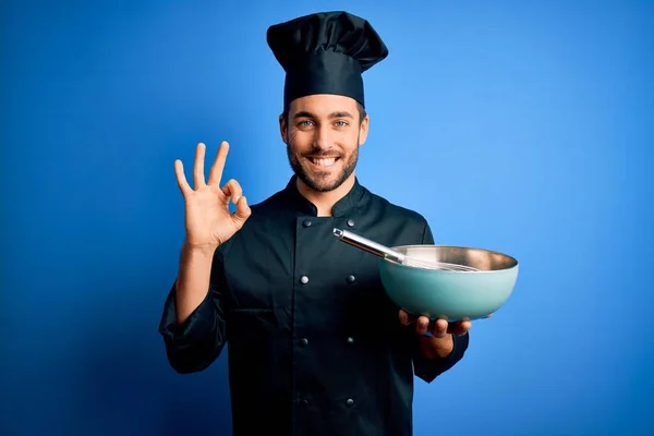 年轻的炊事员 留着胡子 身穿制服 用胡须和碗盖着蓝色背景 手握手签 很好的符号 — 图库照片