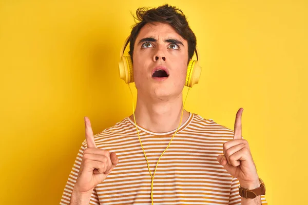 Adolescente Niño Usando Auriculares Sobre Fondo Amarillo Aislado Asombrado Sorprendido —  Fotos de Stock