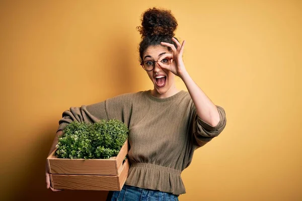 若いです美しいです庭師女性とともに巻き毛とピアス保持木の箱で植物とともに幸せな顔笑顔します — ストック写真