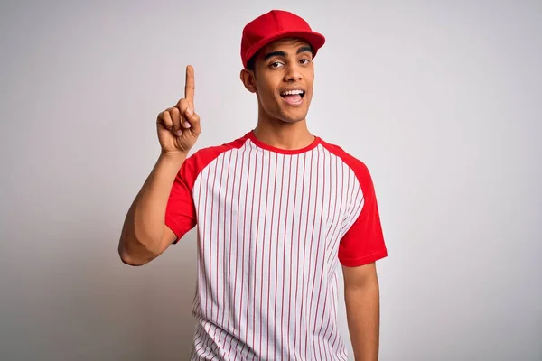 縞模様の野球Tシャツとキャップを着ている若いハンサムなアフリカ系アメリカ人のスポーツマンは 成功したアイデアで指を指しています 興奮し 第一番 — ストック写真