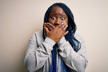 Beyaz arka planda örgü ören Afro-Amerikan kadın örgü örüyor. Ağzı yanlışlıkla ellerle kapatıyor. Gizli konsept.