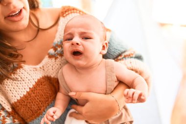Genç ve güzel bir kadın ve bebeği evde. Yeni doğmuş bir bebek ağlıyor ve annesi ona sarılıyor.