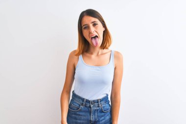 Güzel kızıl saçlı kadın izole edilmiş arka planda duruyor ve komik bir ifadeyle dilini dışarı çıkarıyor. Duygu kavramı.