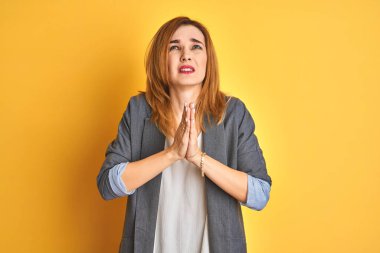 Kızıl saçlı beyaz iş kadını, sarı arka plan üzerinden izole edilmiş esneme, yarı yüz, göz ve ağız kısmını elle kapatmaktan yorulmuş. Yüzüm acıyor..