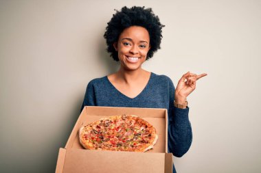 Kıvırcık saçlı, İtalyan pizzalı, elleri ve parmakları kenarı işaret eden Afro-Amerikan bir kadın.