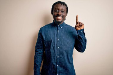 Beyaz arka plan üzerinde duran ve gülümseyen, kendinden emin ve mutlu gülümseyen genç, Afro-Amerikan adam..