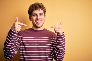 Sarışın, kıvırcık saçlı, sıradan çizgili süveter giyen, kendine güvenen, kendini gururlu ve mutlu gösteren genç bir adam..