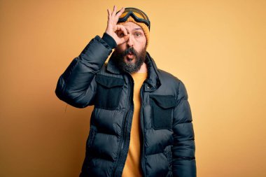 Sakallı, kar maskesi takmış, kar maskesi takmış, kar maskesi takmış yakışıklı kayakçı şaşırmış yüz ifadesiyle şaşırmış, parmaklarından bakan biri. İnançsız ifade.