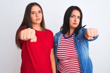 Gündelik giysiler giyen genç güzel kadınlar izole edilmiş beyaz arka planda durup yumruk yumruğa dövüşmek, agresif ve öfkeli saldırı, tehdit ve şiddet.