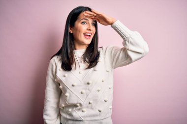 Mavi gözlü genç esmer kadın izole edilmiş pembe arka planda günlük süveter giyiyor. Çok mutlu ve gülümsüyor. Konsept aranıyor.