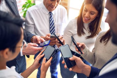 Ofiste el ele duran bir grup iş adamı akıllı telefonları kullanarak semboller yapıyor.