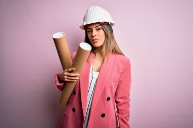 Genç, güzel, esmer, mimar, kasklı bir kadın elinde planlar, akıllı suratında kendine güvenen bir ifade var ve ciddi düşünüyor.