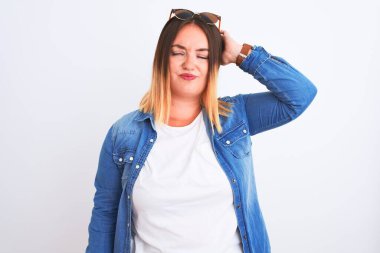 İzole edilmiş beyaz arka plan üzerinde duran kot gömlek giyen güzel bir kadın kafası karışmış ve soru sormayı merak ediyor. Şüpheyle kararsız, kafa kafaya düşünerek. Düşünceli kavram.