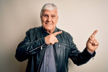 Üst düzey yakışıklı beyaz gömlekli ve ceketli adam izole edilmiş beyaz arka planda gülümsüyor ve kameraya bakıyor iki eliyle ve parmaklarıyla kenarı işaret ediyor..