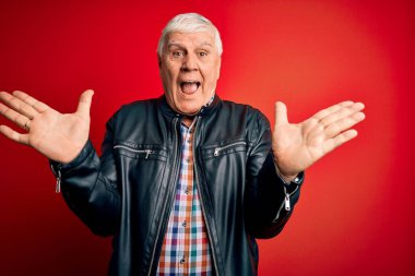 Kıdemli yakışıklı, beyaz gömlekli ve ceketli adam izole edilmiş kırmızı arka planda çılgın ve başarıyı kutlarken kolları havada ve gözleri açık heyecanlı bir şekilde çığlık atıyor. Kazanan konsept