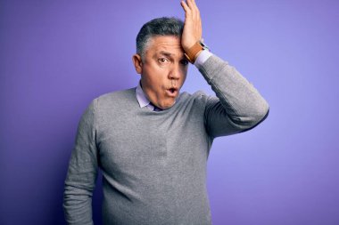 Mor arka planda zarif bir süveter giyen, orta yaşlı, yakışıklı, gri saçlı bir adam. Hatayla el ele tutuşurken şaşırmış. Hatayı hatırla. Unuttum, kötü hafıza konsepti.