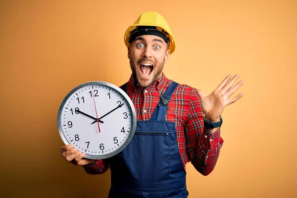 Young Builder Man Wearing Safety Helmet Holding Big Clock Yellow — Stock Photo, Image