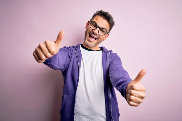 보라색 스웨터와 안경을 잘생긴 남자가 분홍색 손으로 긍정적 행동을 승인하고 — 스톡 사진