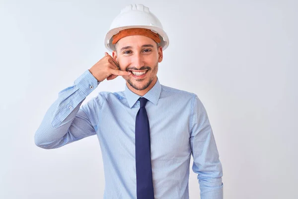 年轻的商人戴着承包商安全帽 带着孤立的背景微笑着 用手和手指做着电话手势 就像在电话里说话一样 交流概念 — 图库照片