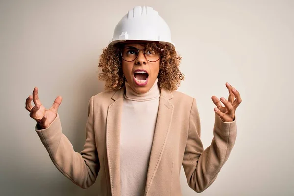 年轻的非洲裔美国卷曲建筑师女人 头戴安全帽 戴着眼镜 疯狂地大喊大叫 带着咄咄逼人的表情和手臂 沮丧的概念 — 图库照片