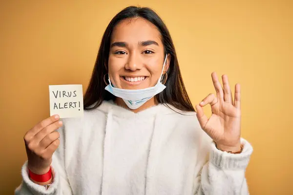 年轻美丽的亚洲女人 戴着医用口罩 手持带有病毒警示信息的文件 手握手签 标志出色 — 图库照片
