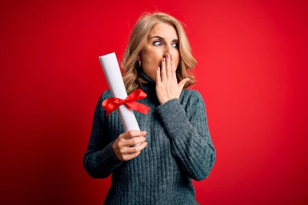 Middle age beautiful blonde student woman holding university graduate diploma cover mouth with hand shocked with shame for mistake, expression of fear, scared in silence, secret concept