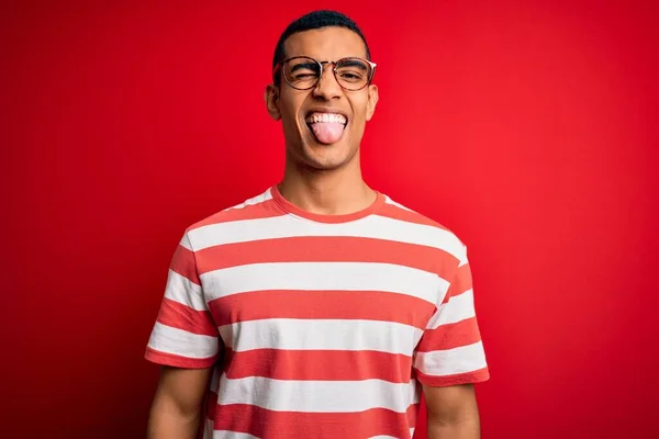 Mladý Pohledný Africký Američan Neformálním Pruhovaném Tričku Brýlích Vystrčeném Jazykem — Stock fotografie