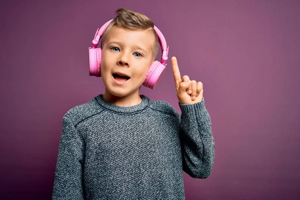 Młody Biały Dzieciak Słuchawkach Słuchający Muzyki Fioletowym Tle Wskazujący Palcem — Zdjęcie stockowe