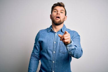 Sakallı, mavi gözlü, sıradan bir kot gömlek giyen genç, yakışıklı sarışın adam kameraya kızgın ve sinirli bir şekilde bakıyor.