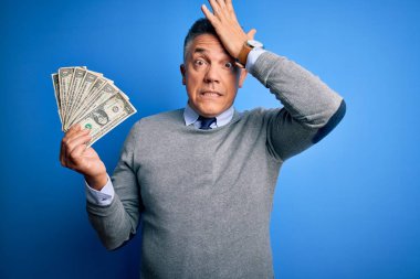 Mavi arka planda bir sürü dolar tutan orta yaşlı, yakışıklı, gri saçlı bir adam. Elleri başının üstünde, utanç ve şaşkınlık dolu, sinirli ve hayal kırıklığına uğramış bir halde. Hata için korku ve üzüntü.