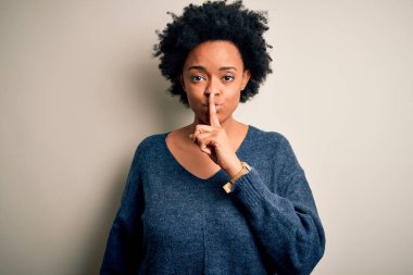 Kıvırcık saçlı, sıradan süveter giyen, dudakları parmaklı, sessiz olmak isteyen güzel Afro-Amerikan bir kadın. Sessizlik ve gizli konsept.