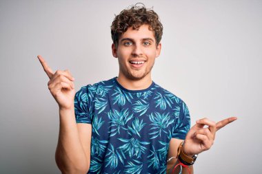 Tatilde, kıvırcık saçlı, yaz tişörtlü, kendine güvenen, farklı yönleri gösteren genç, sarışın, yakışıklı bir adam. Reklam için boşluk kopyala