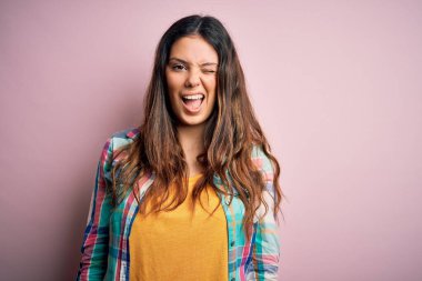 Genç, güzel, esmer, sıradan bir gömlek giyen, pembe arka planda duran, seksi bir ifadeyle kameraya bakan, neşeli ve mutlu yüzlü bir kadın..