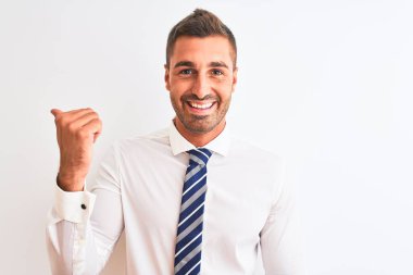 Genç yakışıklı, zarif iş adamı izole edilmiş arka planda gülümseyen, gülümseyen ve baş parmağıyla yan tarafa bakan..