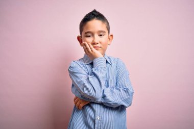 Pembe izole edilmiş arka planda duran zarif tişörtlü genç çocuk kollarını kavuşturarak depresyondan sıkılmış ve yorgun görünüyor..