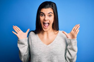 Genç, güzel, esmer bir kadın mavi arka planda dikilmiş çılgın kutlamalar yapıyor ve kollarını kaldırıp heyecanla haykırarak başarıyı kutluyor. Kazanan konsept