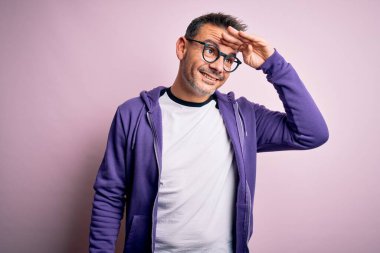 Pembe arka planda duran mor kazak ve gözlük takan yakışıklı genç adam çok mutlu ve tebessüm ediyor. Konsept aranıyor.