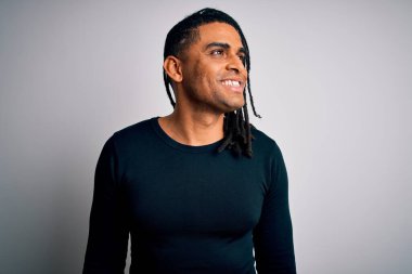 Rastalı siyah süveter giyen, yüzünde gülümseme ve doğal ifadeyle yan yana bakan Afro-Amerikan genç yakışıklı adam. Kendinden emin gülen.