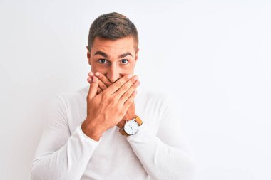 İzole edilmiş arka planda beyaz gömlek giyen genç yakışıklı adam yanlışlıkla elleriyle ağzını kapatırken şok oldu. Gizli konsept.