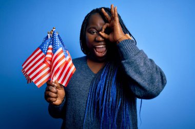Genç, vatansever, Afro-Amerikan, örgülü, mutlu yüzlü, bayrakları olan, elleri gözünün içine bakan ve gülümseyen bir kadın.