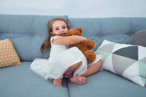 Sevimli Sarışın Bebek Mutlu Gülümsüyor Kanepede Oturup Evde Oyuncak Ayıyla — Stok fotoğraf